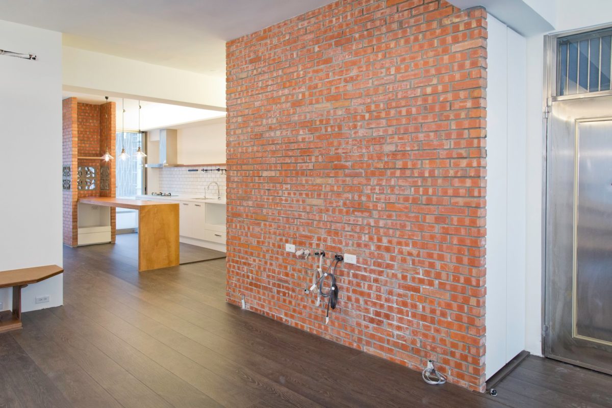 磚牆是用一般紅磚砌成，每一塊磚頭都是經過挑選的。緊鄰電視牆的是開放式的廚房與餐廳。