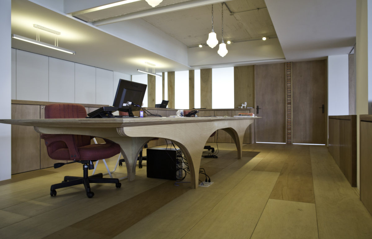 為辦公區設計的辦公大桌!在本設計案中,從木作隔件、書架、各式辦 公桌、廁所隔屏到木地板,都是使用夾板作為主材料,依照夾板特性設 計,木工現場製作完成的